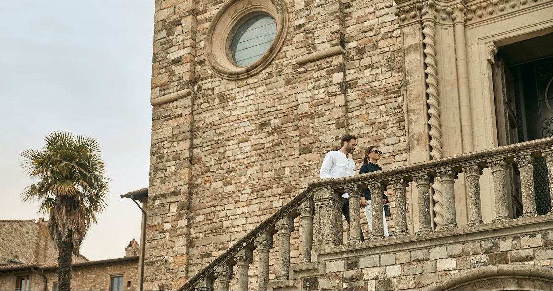 A Man And Woman Standing On A Stone Staircase In Front Of A Building