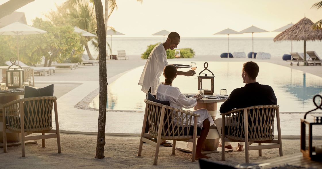 A Group Of People Sitting At A Table Outside