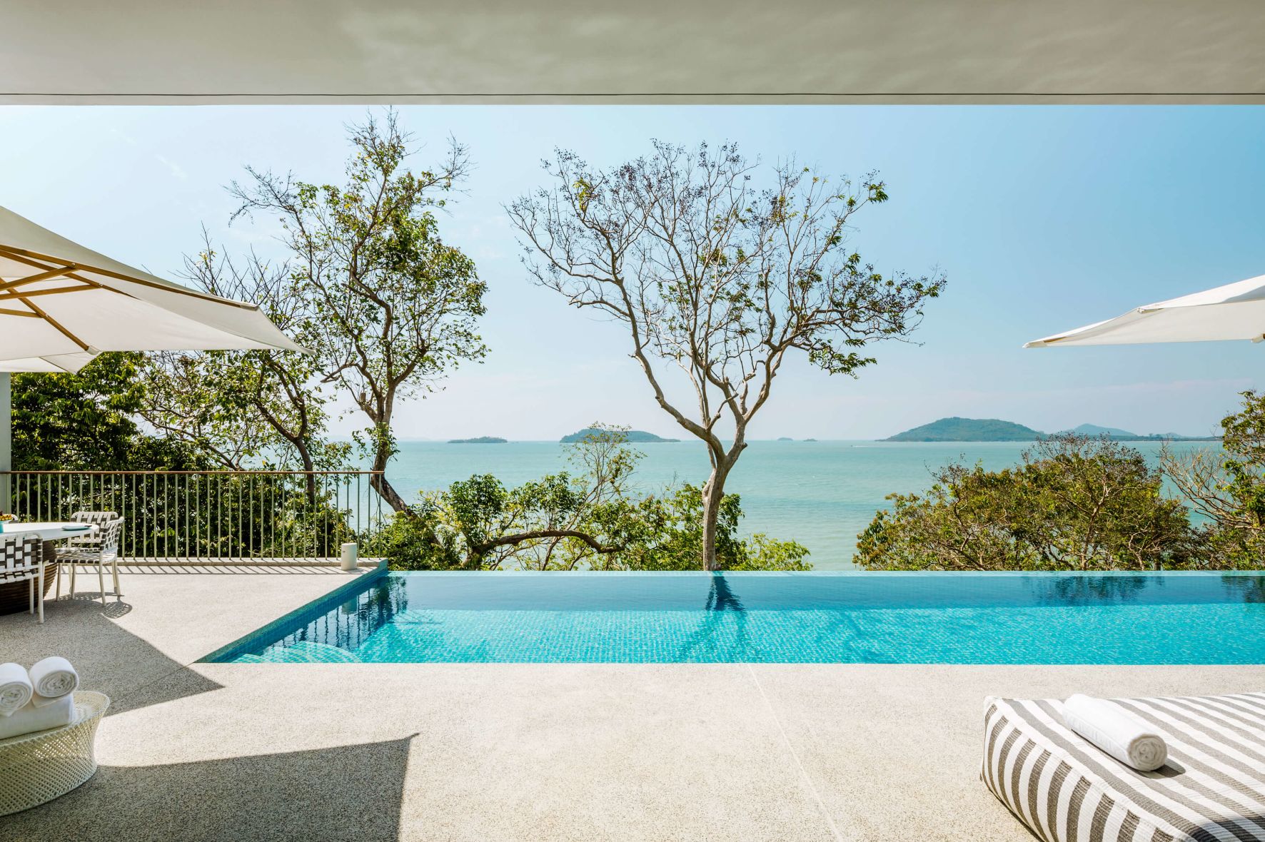 A Pool With A Tree And A Body Of Water In The Background