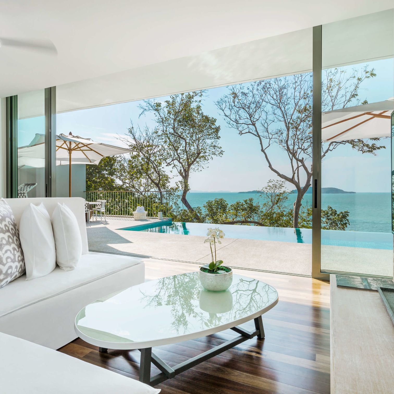 A Room With A Pool And A Large Window With Trees And A Body Of Water In The Background