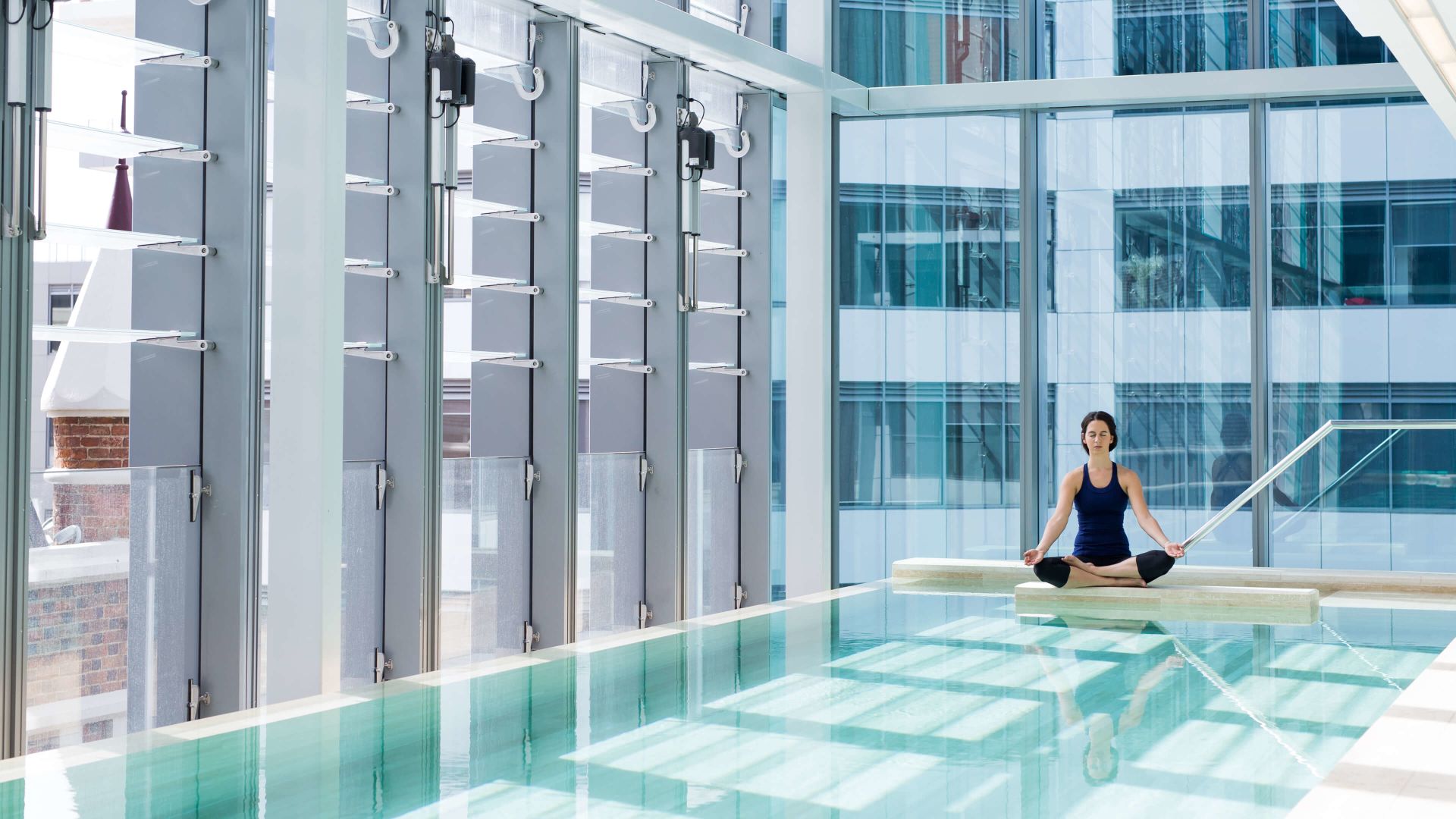 A Person Sitting On A Ledge In A Swimming Pool